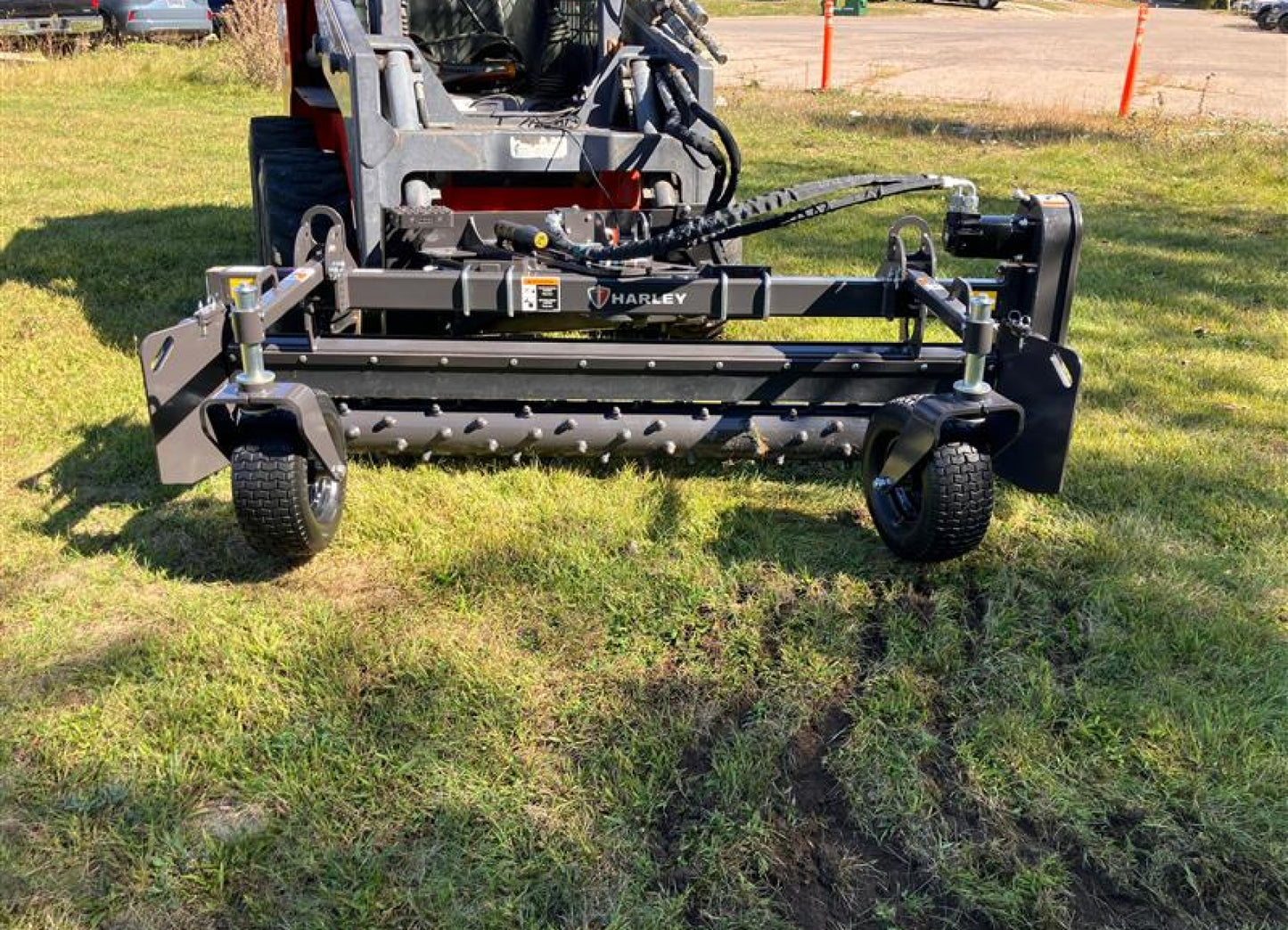 Skid steer power rake attachment for grading topsoil and conditioning soil for seedbeds.