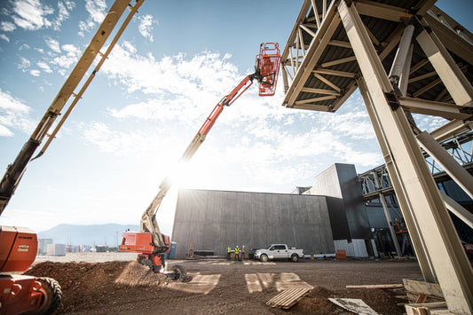 JLG telescopic boom lift working on a Utah job site with the Wasatch range behind it